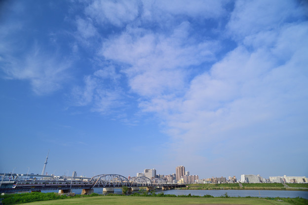 空を埋める雲と荒川橋梁を渡る京成電車